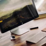 Workspace with wood desk, computer, keyboard, and mouse for person to make $15,000 a year.
