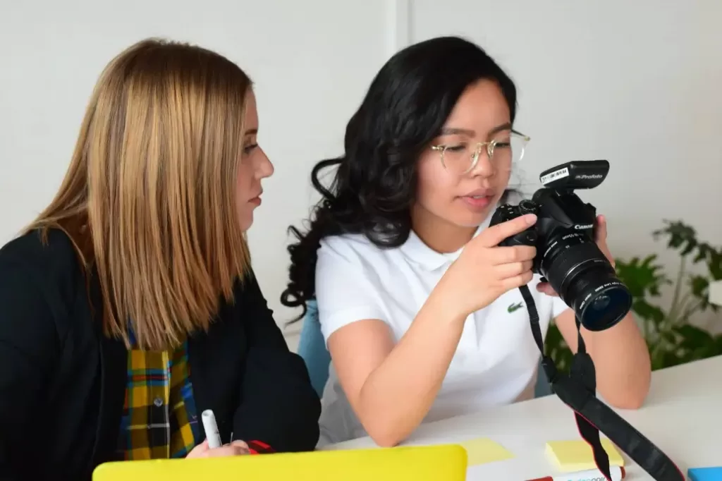 Two women working with a camera while earning $70,000 a year.