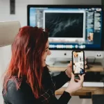 Woman with red hair and phone earning $72,000 a year.