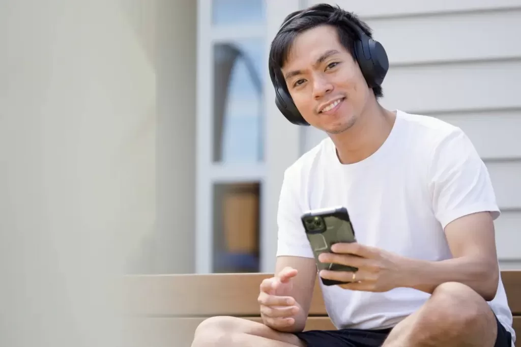 Man with a phone and headphones that makes $75,000 a year.