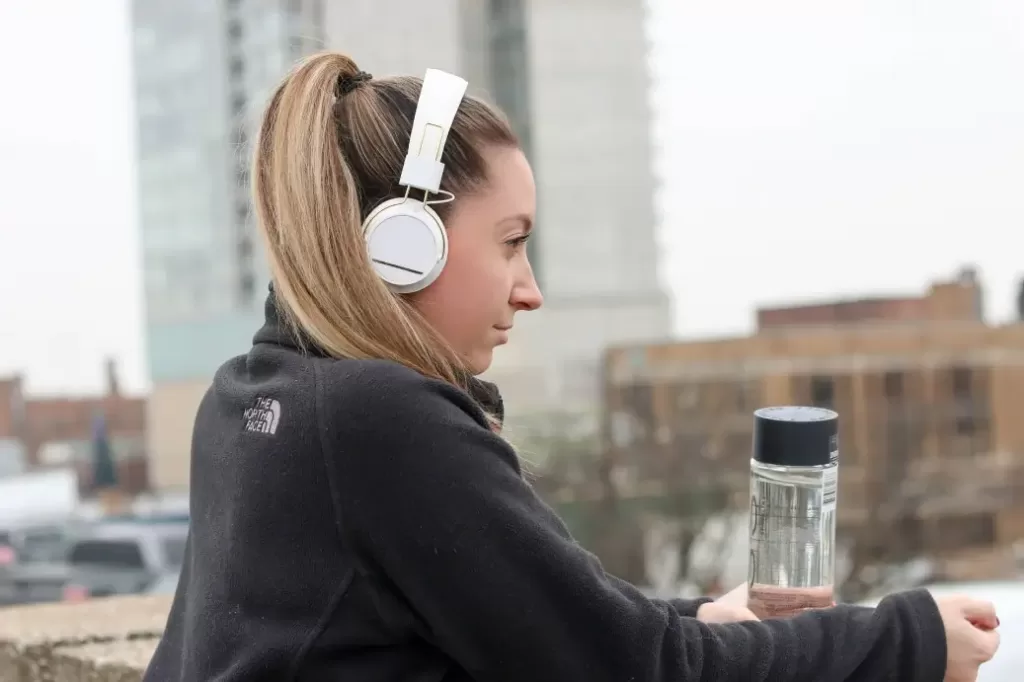 Woman with a water bottle and headphones earning $79,000 a year.