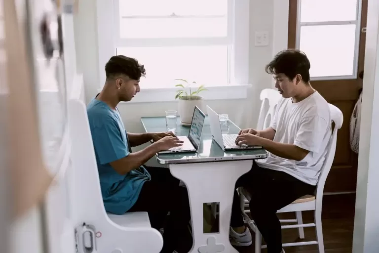 Two men sitting and working on laptops earning $96,000 a year.