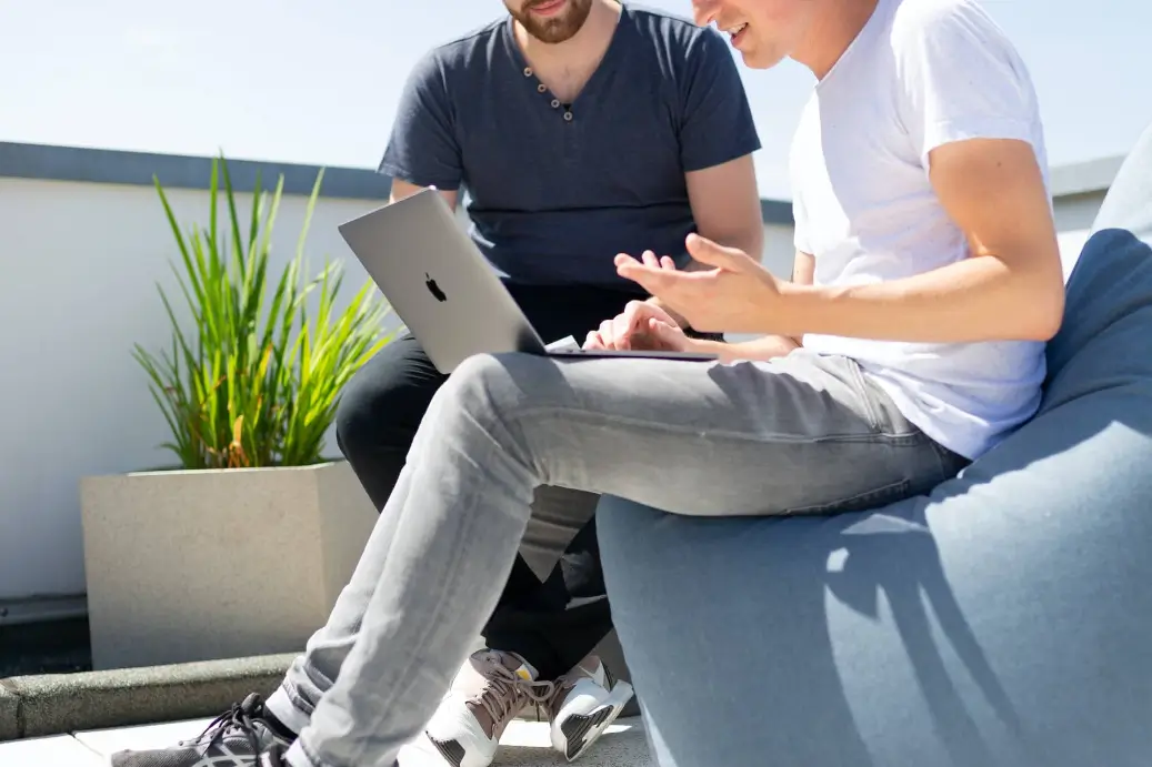 Two people working on a laptop making $98,000 a year.
